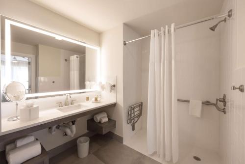 a white bathroom with a sink and a mirror at Homewood Suites by Hilton Palm Beach Gardens in Palm Beach Gardens