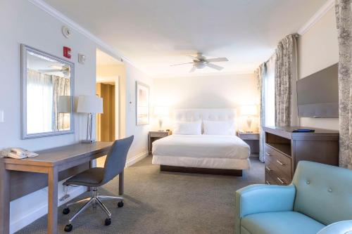a hotel room with a bed and a desk and a chair at Homewood Suites by Hilton Palm Beach Gardens in Palm Beach Gardens