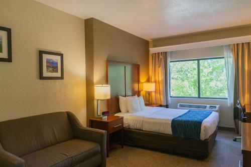 a hotel room with a bed and a chair and a window at Comfort Inn North - Air Force Academy Area in Colorado Springs