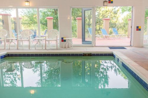 a swimming pool with chairs and a table and windows at Comfort Inn North - Air Force Academy Area in Colorado Springs