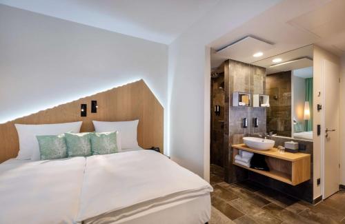 a bedroom with a white bed and a sink at ARCOTEL HafenCity Dresden in Dresden