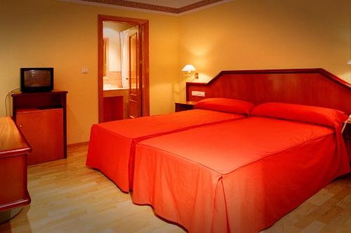 a red bed in a room with a television at Hotel Torrepalma in Alcalá la Real