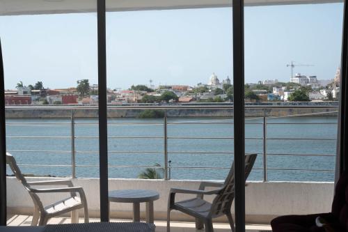 a room with chairs and a table and a view of a river at Bahia 79 Apartasuites Cerca al Centro in Cartagena de Indias