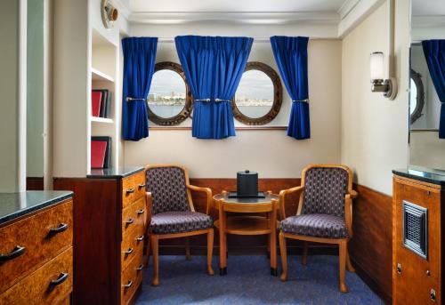 two chairs and a table in a room with blue curtains at The Queen Mary in Long Beach