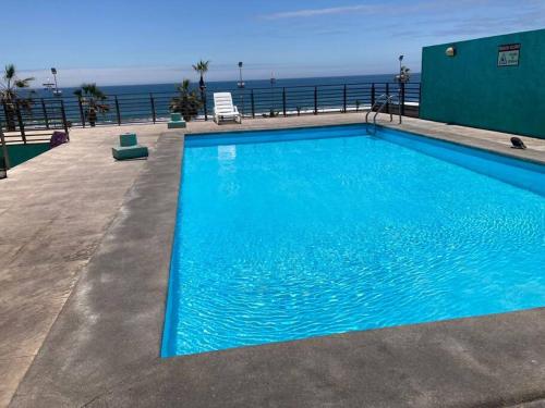 a blue swimming pool with the ocean in the background at Bella vista departamento amoblado in Iquique