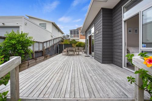 a deck with chairs and tables on a house at Relax on Dillon - Waihi Beach Holiday Home in Waihi Beach