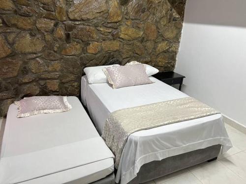 duas camas num quarto com uma parede de pedra em Cabaña de descanso, Rodadero em Gaira