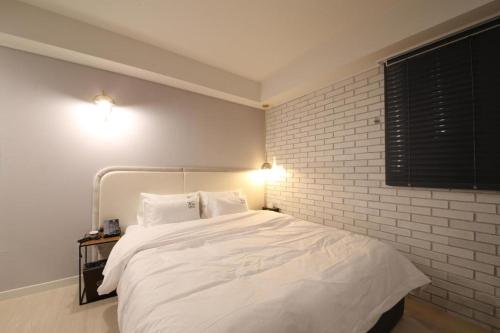 a bedroom with a white bed and a brick wall at No.25 Hotel Busan Seomyeon in Busan