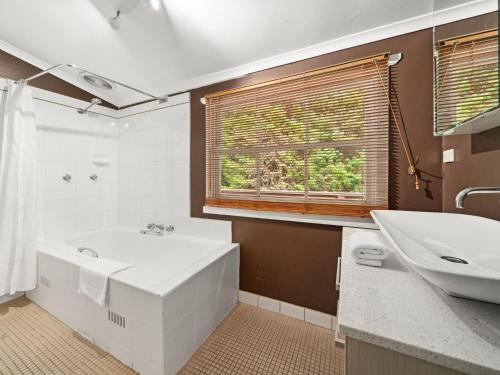 ein Bad mit einer Badewanne, einem Waschbecken und einem Fenster in der Unterkunft In the Blue in Blackheath
