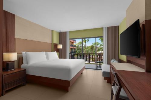 a bedroom with a bed and a tv and a balcony at Courtyard by Marriott Phuket, Patong Beach Resort in Patong Beach