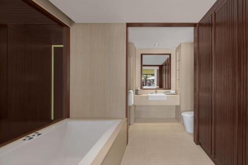 a bathroom with a tub and a toilet and a sink at Courtyard by Marriott Phuket, Patong Beach Resort in Patong Beach