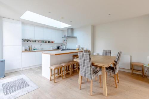 a kitchen and dining room with a wooden table and chairs at Lovely 2BD House on Private Road Clapham Common! in London