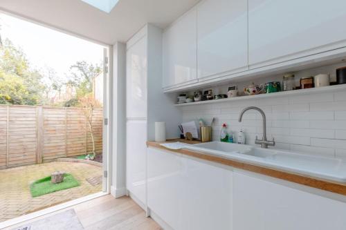 a kitchen with a sink and a large window at Lovely 2BD House on Private Road Clapham Common! in London