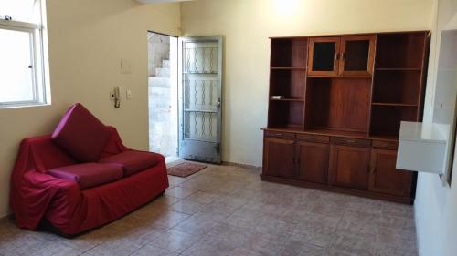 ein Wohnzimmer mit einem roten Stuhl und einem Schrank in der Unterkunft Hospedagem do Marcão in Belo Horizonte