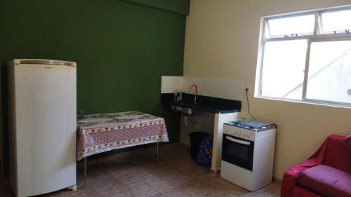 eine Küche mit einem Waschbecken und einem Tisch in einem Zimmer in der Unterkunft Hospedagem do Marcão in Belo Horizonte