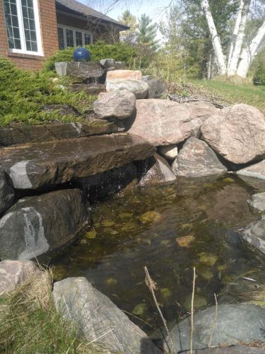 a stone bridge over a pond in front of a house at Waterfront Hideaway Private Suite-King bed room in Tottenham