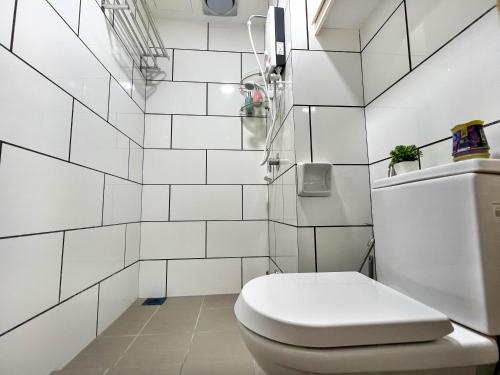a white toilet in a bathroom with white tiles at Modern Muji Home Retreat near Taiping Lake Garden with Free Netflix in Taiping