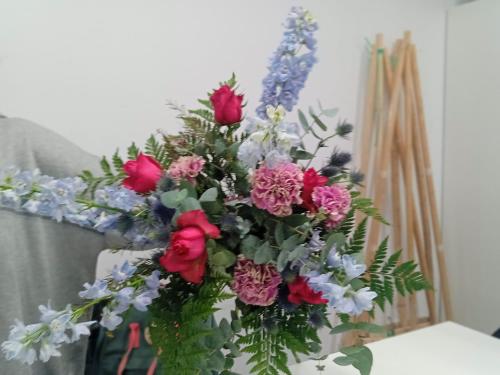 a vase filled with red roses and other flowers at Habitación acogedora por días in Madrid