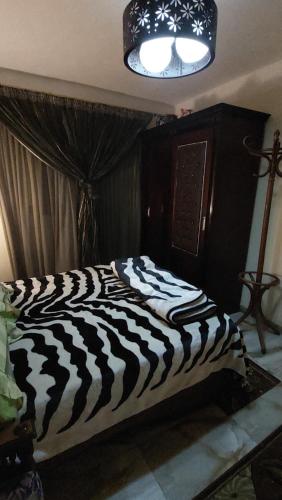 ein Bett mit Zebramuster in einem Schlafzimmer mit einer Lampe in der Unterkunft night holiday in in Alexandria