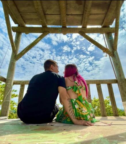 a man and a woman sitting on the ground at Chalé aconchegante, pertinho da cidade e conectada a natureza in Brasilia
