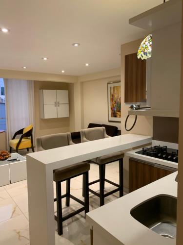 a kitchen and living room with a counter and chairs at Apartamentos Valery in Trujillo