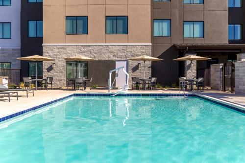 a swimming pool with chairs and umbrellas in front of a building at Residence Inn by Marriott Fairfield Napa in Fairfield