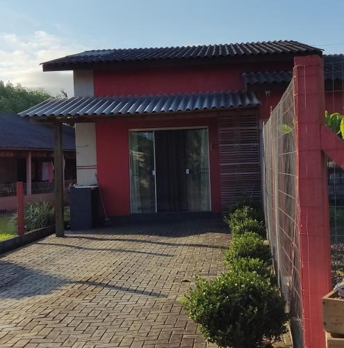 una casa roja con una valla y una entrada de ladrillo en uma casa na viagem, en Três Cachoeiras