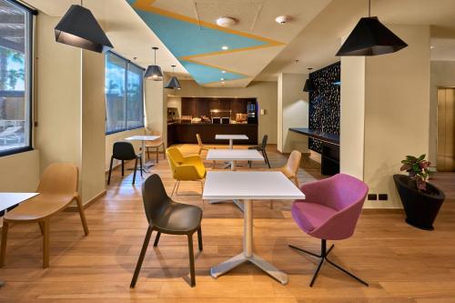 a waiting area with tables and chairs in a building at City Express Plus by Marriott Cabo San Lucas in Cabo San Lucas