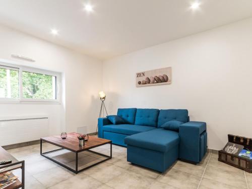 a living room with a blue couch and a table at Maison calme, rénovée, proche Clisson – 3 chambres, terrasses, jardin, pétanque, stationnement privé - FR-1-306-1208 in Clisson