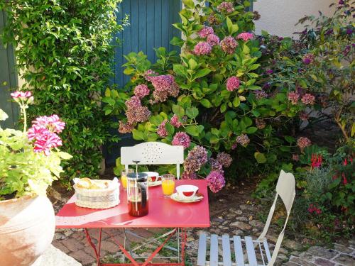 une table et des chaises rouges dans un jardin fleuri dans l'établissement Gîte Montmirail, 3 pièces, 4 personnes - FR-1-410-211, à Montmirail