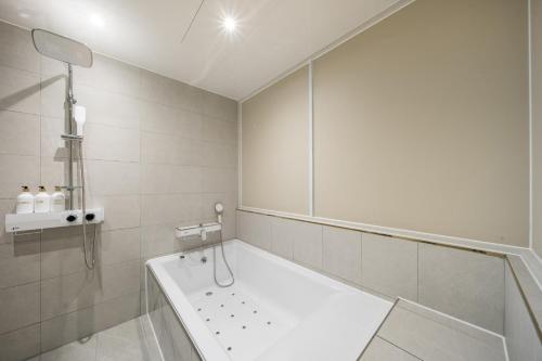 La salle de bains blanche est pourvue d'une baignoire et d'une douche. dans l'établissement Hey Gunsan Hotel, à Gunsan