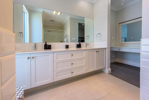 ein Badezimmer mit zwei Waschbecken und einem großen Spiegel in der Unterkunft A Waterside Paradise - Geographe's Hidden Oasis in Geographe