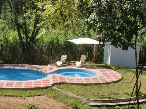 una piscina en un patio con 2 sillas y una sombrilla en Nueva Tierra, Ayampe-Suite en Las Tunas