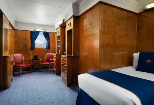 a hotel room with a bed and a table and chairs at The Queen Mary in Long Beach