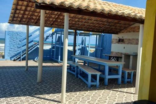 uma mesa de piquenique e bancos debaixo de um guarda-sol na praia em Casa BRISA DO MAR Abaís em Praia Da Caueira