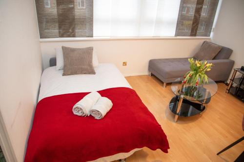a bedroom with a bed with a red and white blanket at Large and bright one bedroom apartment with free parking! in London