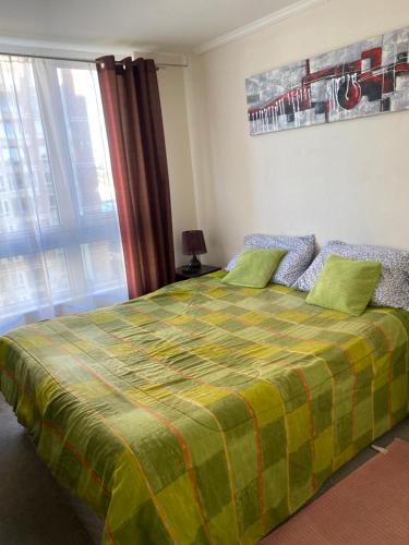 um quarto com uma cama com um cobertor verde e amarelo em Brisas del sol em Talcahuano