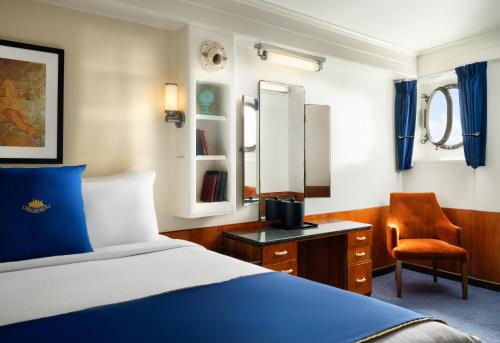 a bedroom with a bed and a desk and a chair at The Queen Mary in Long Beach