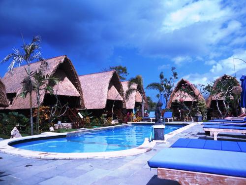 a resort with a swimming pool with blue chairs at Harta Lembongan Villas in Nusa Lembongan