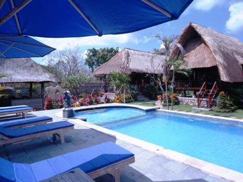 a swimming pool with chairs and an umbrella at Harta Lembongan Villas in Nusa Lembongan