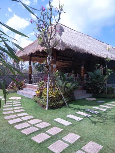 a pathway leading to a house with a thatch roof at Harta Lembongan Villas in Nusa Lembongan