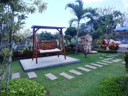 a bench sitting in a garden with a grass yard at Harta Lembongan Villas in Nusa Lembongan