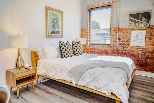 Un dormitorio con una cama y una pared de ladrillo. en The Hive 207 Bees Knees, en Wilmington