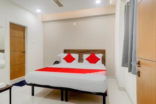 a bedroom with a bed with red pillows at Super OYO Flagship Prime Time Hotel in Kukatpalli