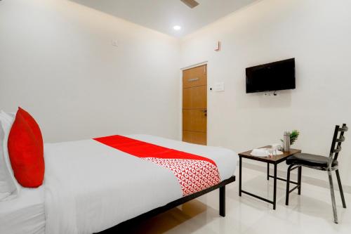 a bedroom with a bed and a chair and a television at Super OYO Flagship Prime Time Hotel in Kukatpalli