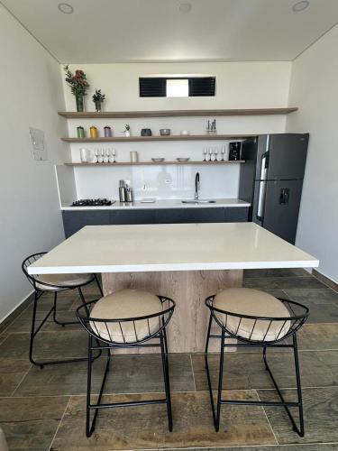 a kitchen with a large white table and two chairs at Montecielo Hosting in Guatapé