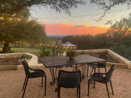 una mesa negra y sillas con puesta de sol en el fondo en V700 Ranch Stays (Guesthouse)-A Tucked Away Gem, en Marble Falls