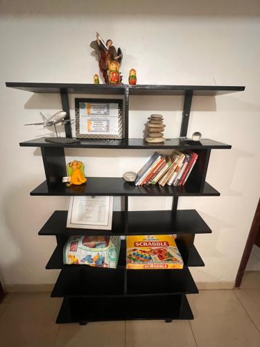 a black book shelf with books on it at Apartamento Aeropuerto Maiquetia en Planta Baja in Catia La Mar