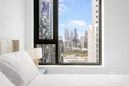 een slaapkamer met een groot raam met uitzicht op de stad bij 2 Bedroom Apartment in Southbanks Stature Building in Melbourne