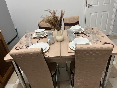 a wooden table with plates and glasses on it at Comfortable, spacious 2 Bedroom house close to Etihad Stadium in Stalybridge